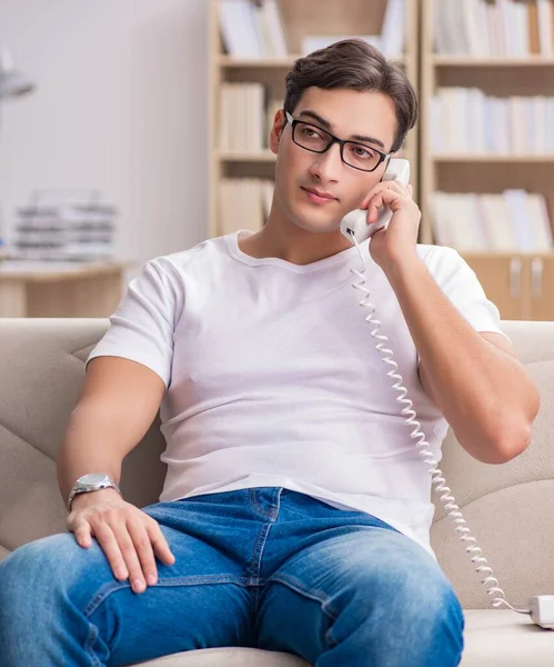 Giovane uomo che parla al telefono sdraiato sul divano — Foto Stock