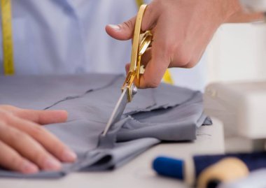 Genç terzi yeni elbiseler üzerinde çalışıyor.