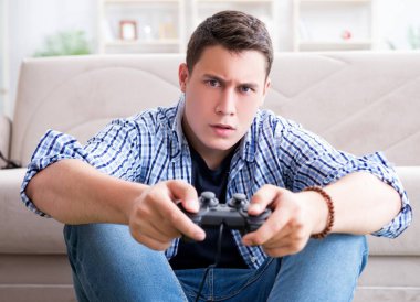 Genç adam evde bilgisayar oyunu oynuyor.