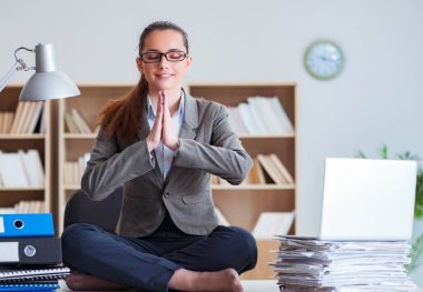 İş kadını ofiste meditasyon yapıyor.