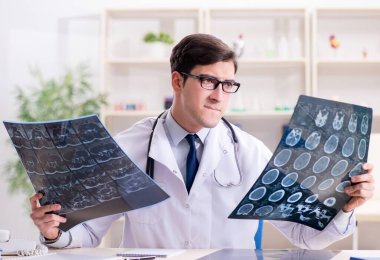 Genç doktor klinikteki röntgen görüntülerine bakıyor.