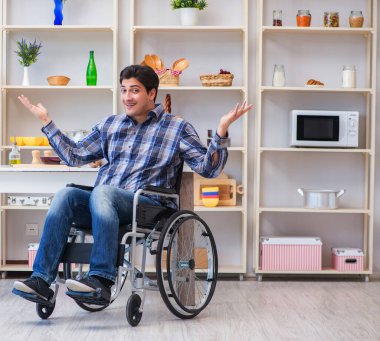 Engelli genç koca mutfakta çalışıyor.