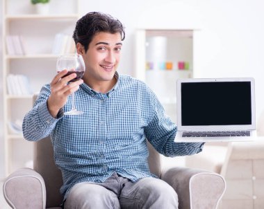 Genç adam evde şarap içiyor.