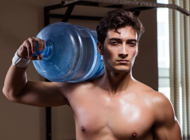 Büyük su şişeli kaslı adam.