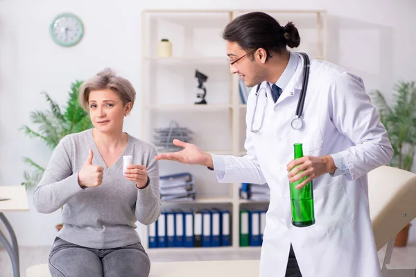Mulher alcoólica visitando jovem médico masculino — Fotografia de Stock