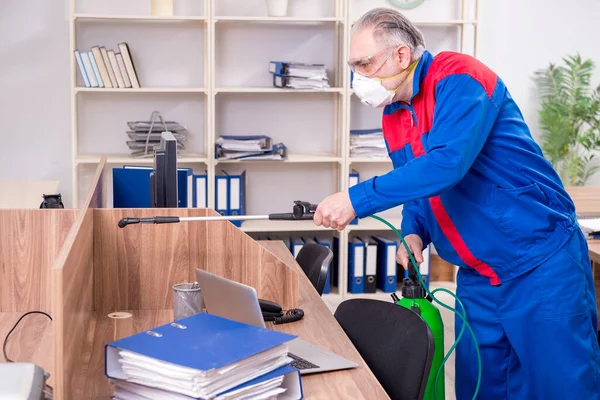 Velho empreiteiro profissional fazendo controle de pragas no escritório — Fotografia de Stock