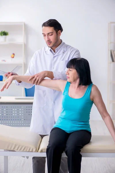 Joven médico masculino examinando paciente anciano femenino —  Fotos de Stock