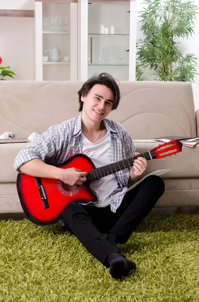 Fiatal férfi gitárral otthon — Stock Fotó