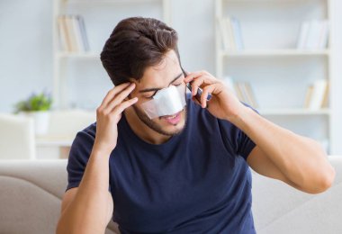 Genç adam estetik cerrahi burnundan sonra evde iyileşiyor.