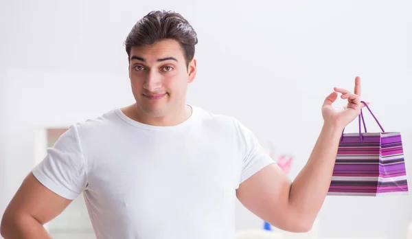 Young man with gift bag at home preparing suprise for wife — Stock Photo, Image