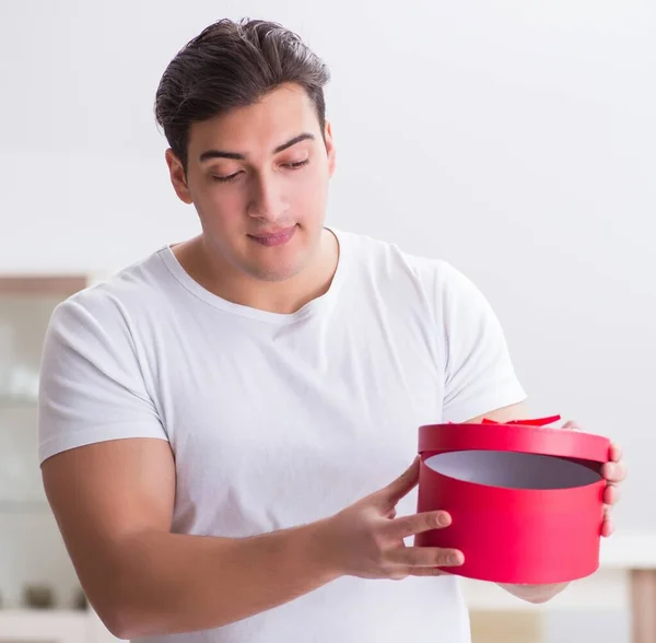 Joven con bolsa de regalo en casa preparando sorpresa para la esposa — Foto de Stock