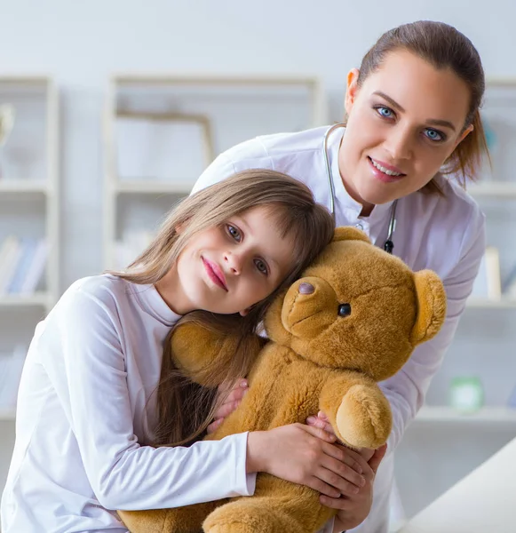 Vrouw vrouwelijke arts onderzoeken klein schattig meisje met speelgoed beer — Stockfoto