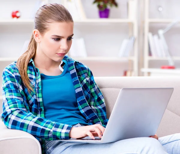 Vrouwelijke student zittend op de bank met laptop — Stockfoto