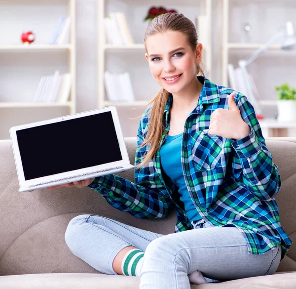 Vrouwelijke student zittend op de bank met laptop — Stockfoto