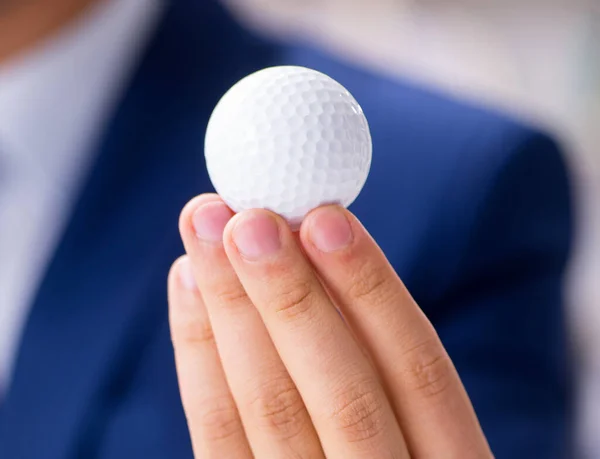 Young businessman with golf ball working in office — Stock Photo, Image