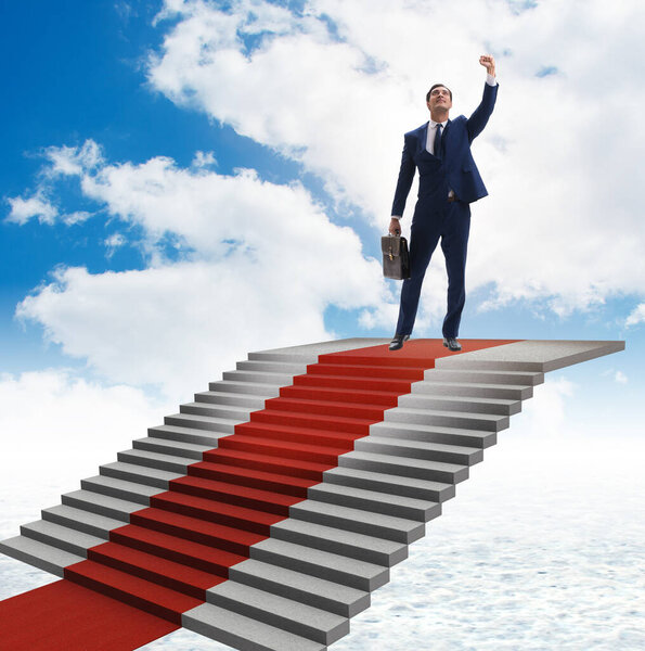 Young businessman climbing stairs and red carpet into sky
