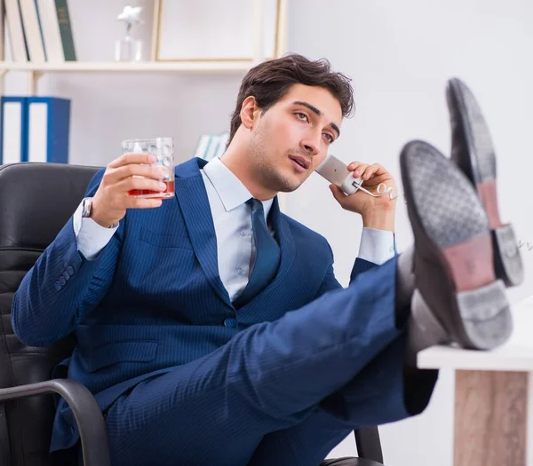 Ung affärsman anställd dricker på kontoret vid skrivbordet — Stockfoto