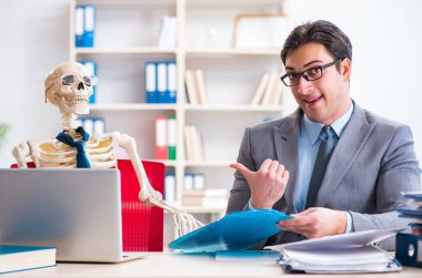 İskeletle çalışan bir iş adamı.