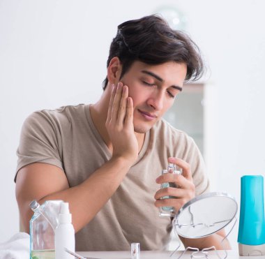 Genç yakışıklı adam aynaya bakıyor.