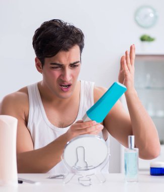 Genç yakışıklı adam aynaya bakıyor.