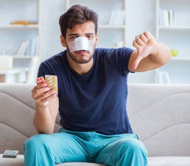 Genç adam estetik cerrahi burnundan sonra evde iyileşiyor.