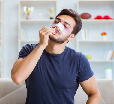 Genç adam estetik cerrahi burnundan sonra evde iyileşiyor.