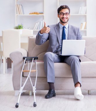 Koltuk değneği ve kırık bacağı olan bir iş adamı.