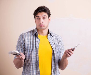 Evdeki duvara alçı yapıştıran genç adam.