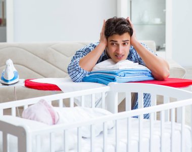 Genç baba yeni doğan bebeğe bakıyor.