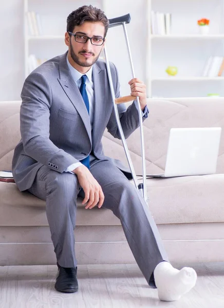 Empresario con muletas y pierna rota en casa trabajando —  Fotos de Stock