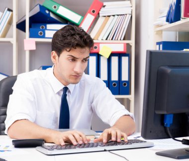 Ofiste kitap ve kağıtlarla çalışan bir işadamı.