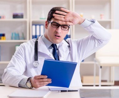 Genç doktor ofiste oturuyor.