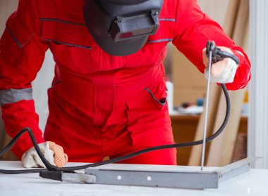 Kaynak tabancası elektrot ve kask takan genç bir tamirci.