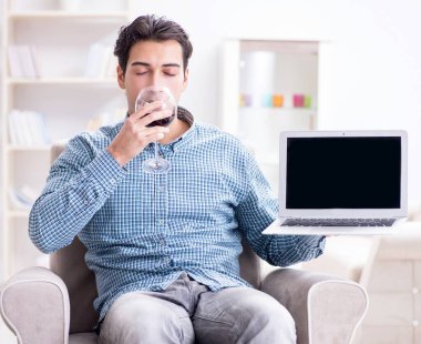 Genç adam evde şarap içiyor.