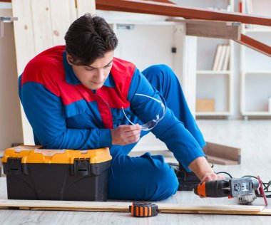 Genç marangoz ahşap kalaslarla çalışmaya ara veriyor.