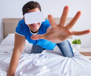 Yatakta sanal gerçeklik başlığı takan genç bir adam.