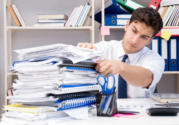 Бизнесмен, работающий в офисе с грудами книг и бумаг — стоковое фото
