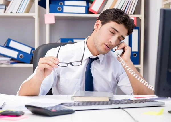 Geschäftsmann arbeitet im Büro mit Stapeln von Büchern und Papieren — Stockfoto