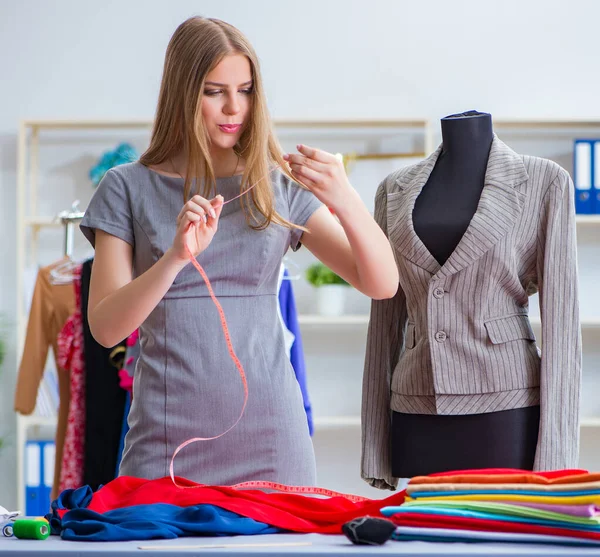 Mujer joven sastre trabajando en taller sobre vestido nuevo — Foto de Stock