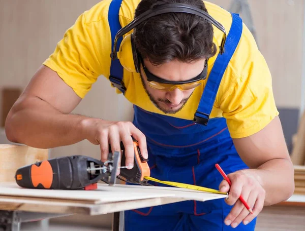 Genç bir marangoz dairesel testereyle odun kesiyor.