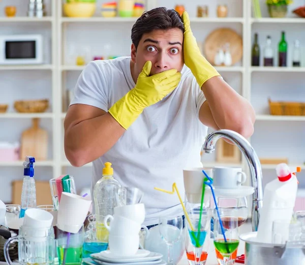 Человек расстроен из-за необходимости мыть посуду — стоковое фото