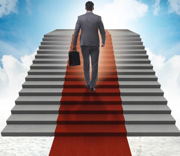Молодой бизнесмен поднимается по лестнице и красной ковровой дорожке в небо — стоковое фото