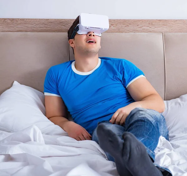 Jovem na cama vestindo um vr realidade virtual head set — Fotografia de Stock