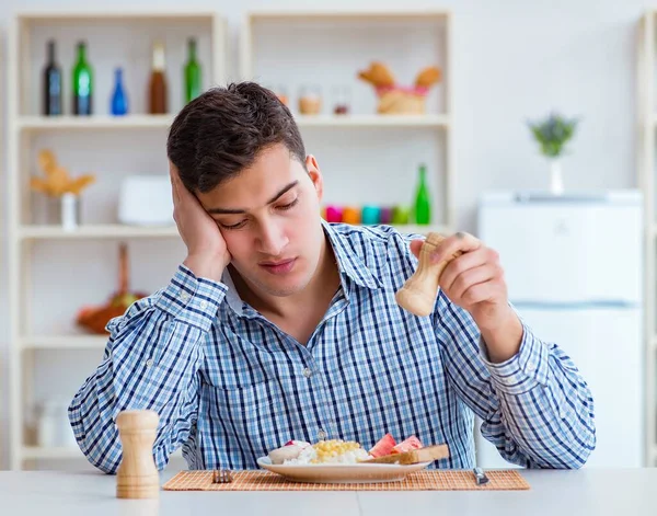 Junger Mann isst zu Hause zu Mittag geschmackloses Essen — Stockfoto