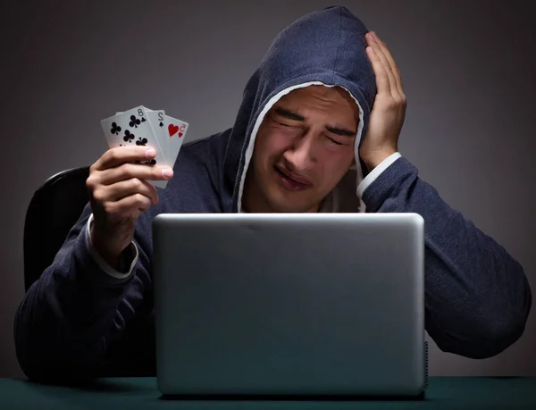 Jovem usando um capuz sentado na frente de um computador portátil — Fotografia de Stock