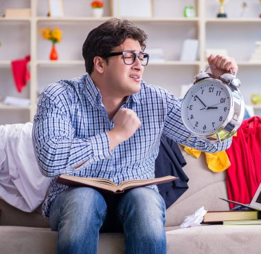 Genç adam dağınık bir odada çalışıyor.