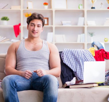 Genç adam dağınık bir odada çalışıyor.