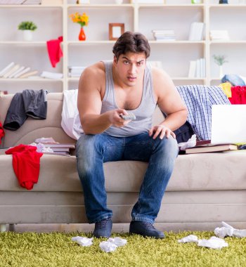 Genç adam dağınık bir odada çalışıyor.