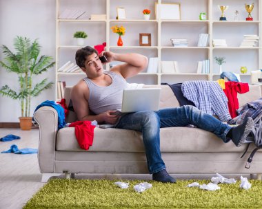 Genç adam dağınık bir odada çalışıyor.