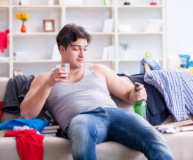 Dağınık bir odada alkol alan genç bir öğrenci.